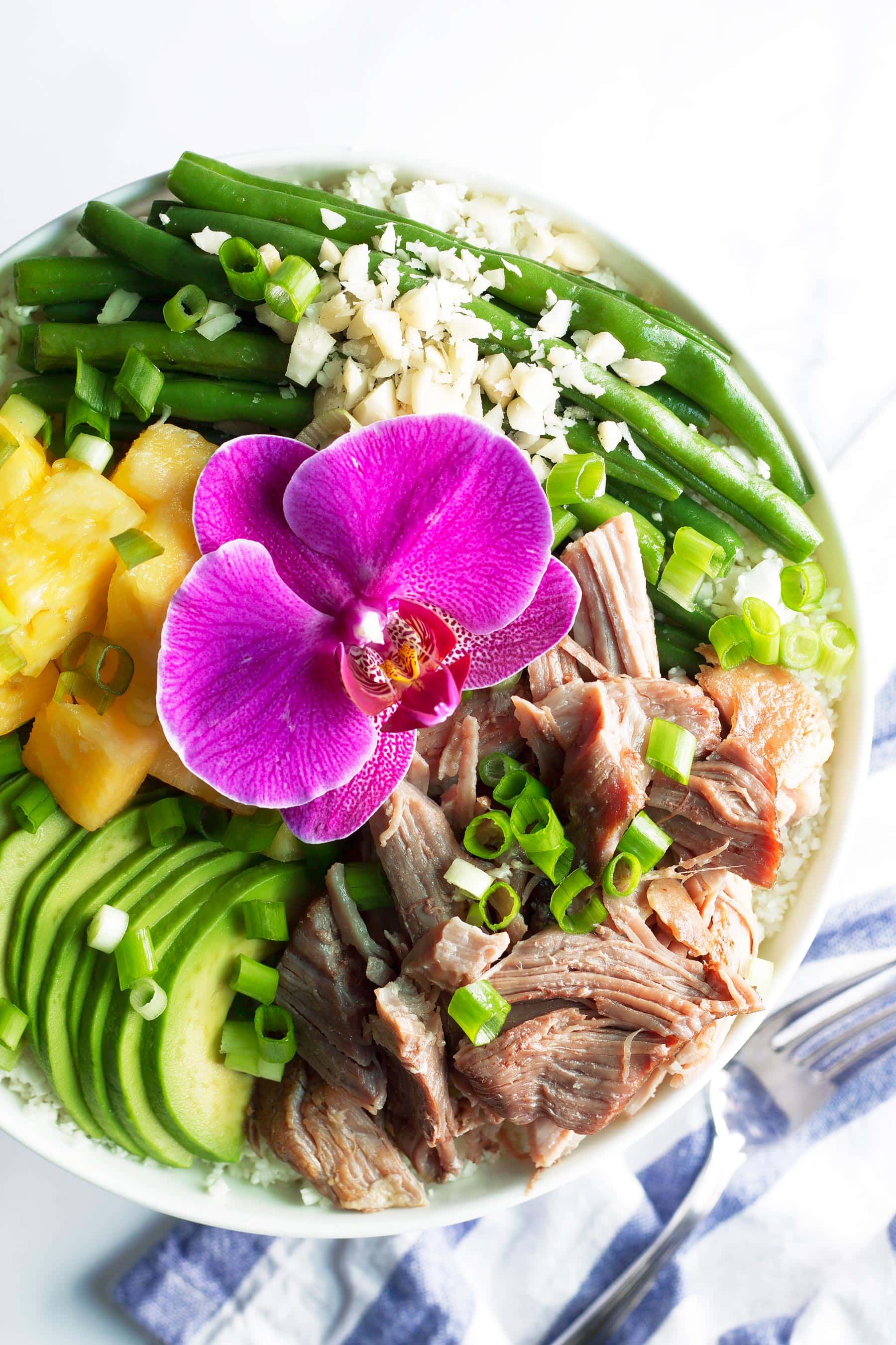 Tender, succulent Kalua pork made right in the Instant Pot! This #Whole30 and #paleo dinner recipe only takes 10 mins of prep time and is great for meal prep! These bowls are made with pork shoulder, pineapple, avocado, long beans, green onion, and macadamia nuts. All on a bed of delicious cauliflower rice! #paleodinner #whole30dinner #instantpot #whole30instantpot #kaluapig #kaluapork #healthyeating #healthydinner #mealprep #mealprepideas #pineapple #hawaiianrecipes #whole30recipes #instantpotrecipes #paleorecipes #glutenfreedinner #macadamianuts #cauliflowerrice