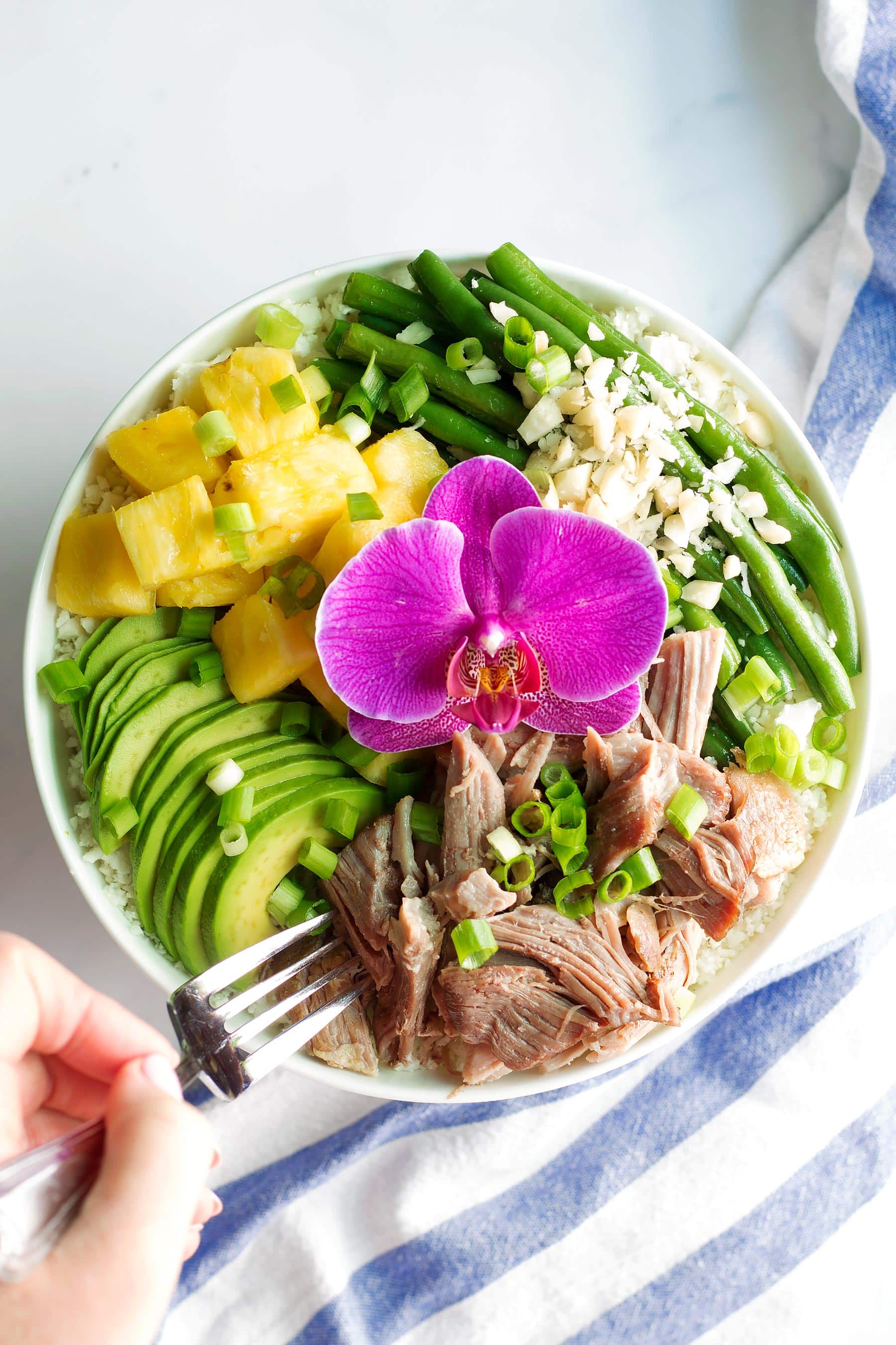 Tender, succulent Kalua pork made right in the Instant Pot! This #Whole30 and #paleo dinner recipe only takes 10 mins of prep time and is great for meal prep! These bowls are made with pork shoulder, pineapple, avocado, long beans, green onion, and macadamia nuts. All on a bed of delicious cauliflower rice! #paleodinner #whole30dinner #instantpot #whole30instantpot #kaluapig #kaluapork #healthyeating #healthydinner #mealprep #mealprepideas #pineapple #hawaiianrecipes #whole30recipes #instantpotrecipes #paleorecipes #glutenfreedinner #macadamianuts #cauliflowerrice