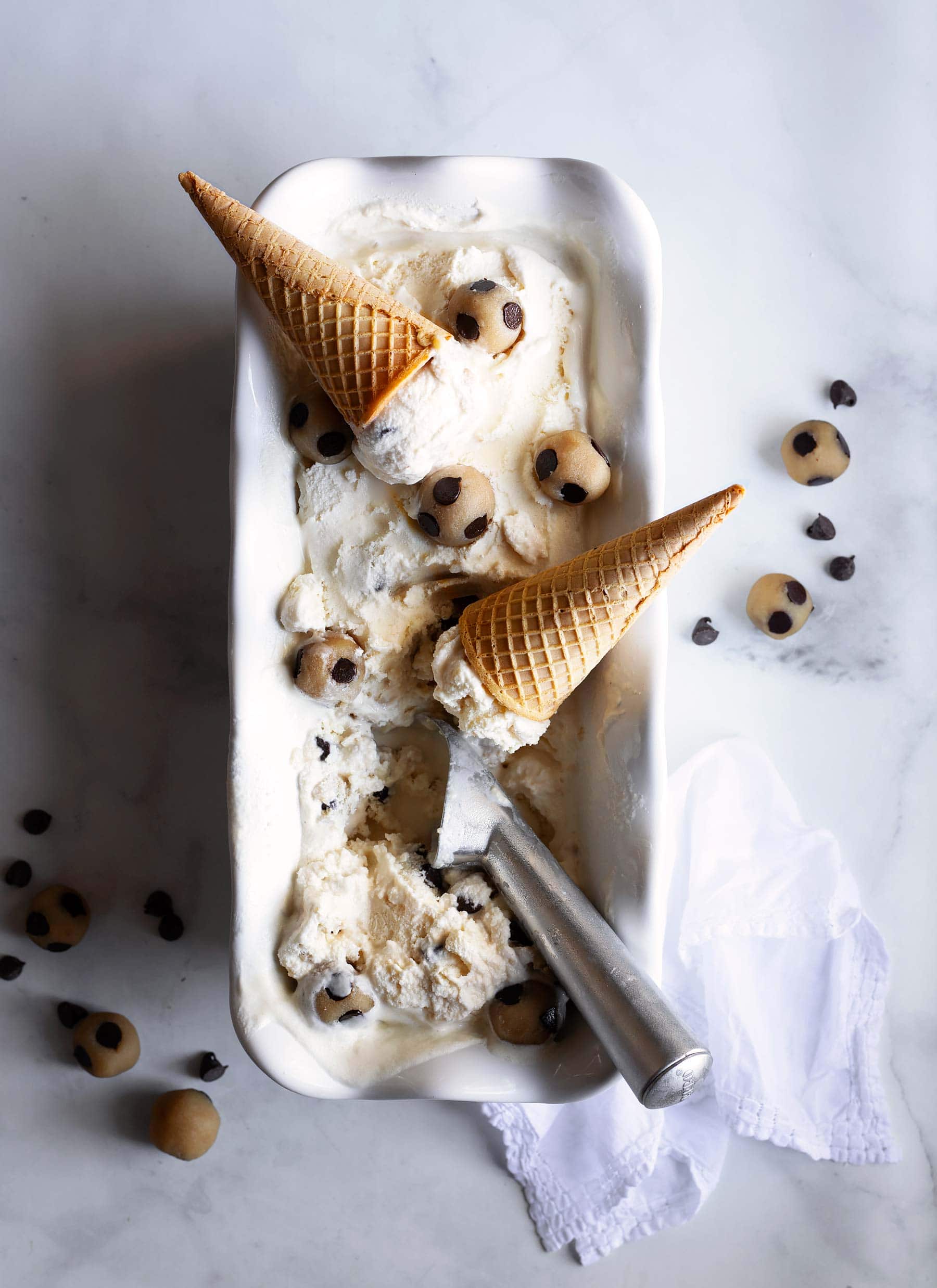 Keto Cookie Dough Ice Cream with cones and scoop on a white serving dish