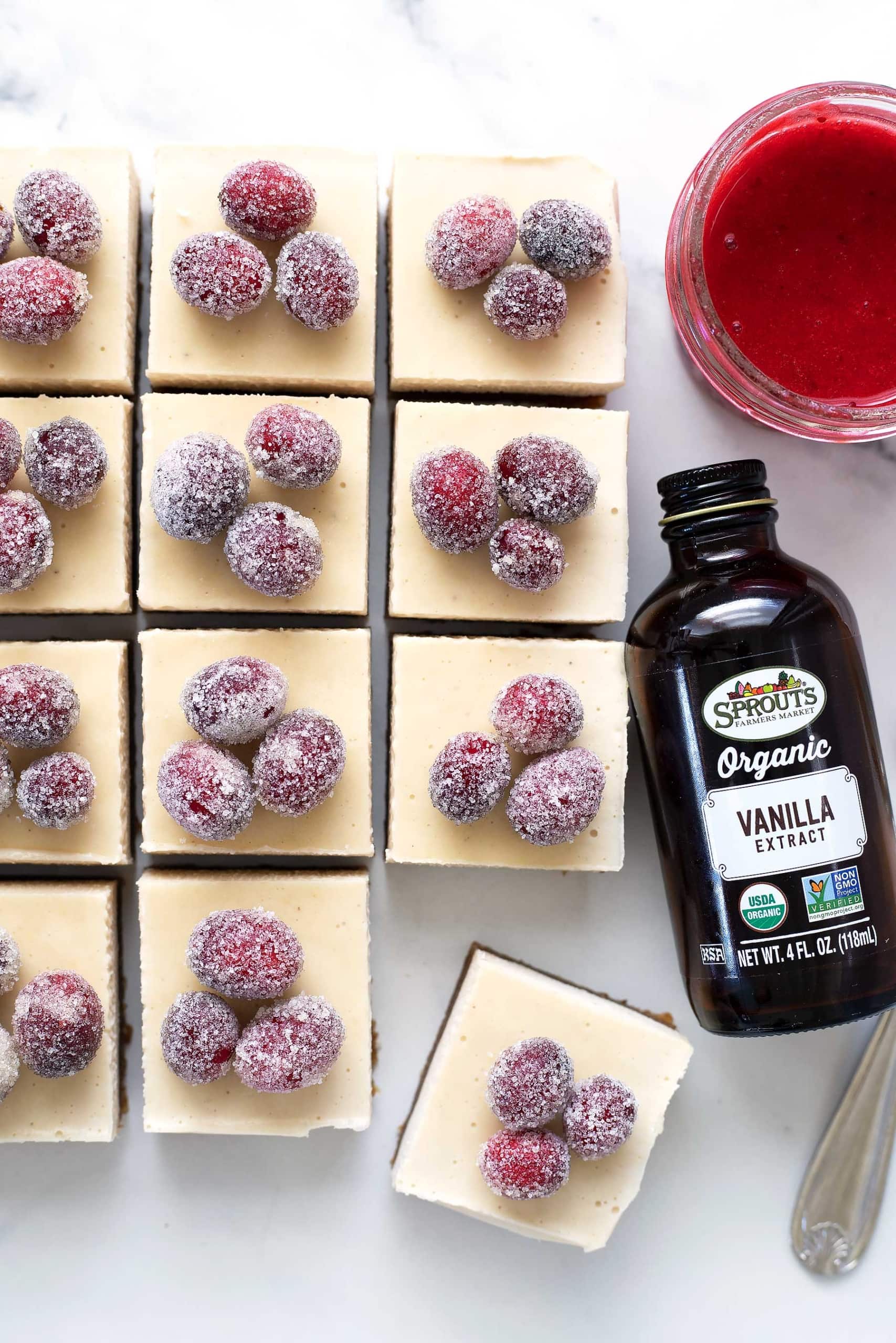 slices of No-Bake Christmas Cheesecake Bars with bottle of Sprouts Organic Vanilla Extract