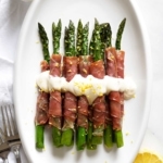 Prosciutto-Wrapped Asparagus on serving dish with lemon cream sauce