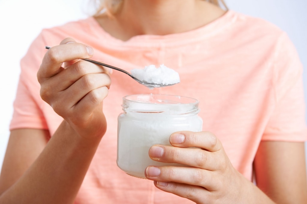 Close Up Of Woman With Spoonful Of Coconut Oil as a Healthy alternative to sugar 