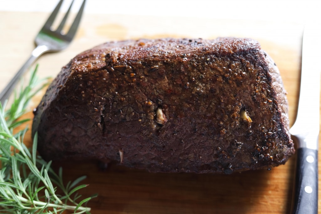 roast beef after cooking before slicing on cutting board with carving knife