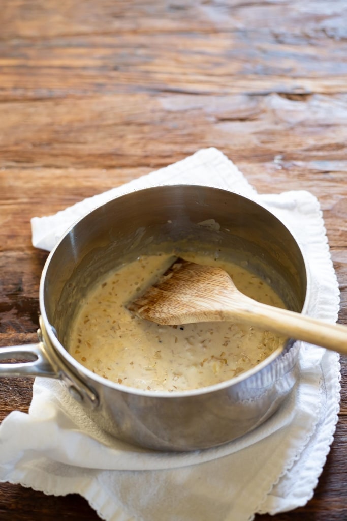 garlic cream sauce in a saucepan with wooden flat head spoon