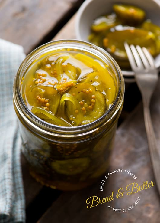 bread and butter pickles in jar on table with fork and blue kitchen towel