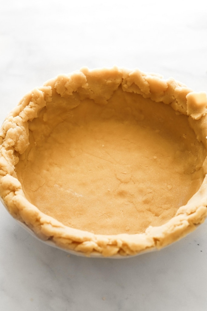 gluten free pie crust in white pie pan before fluting edges