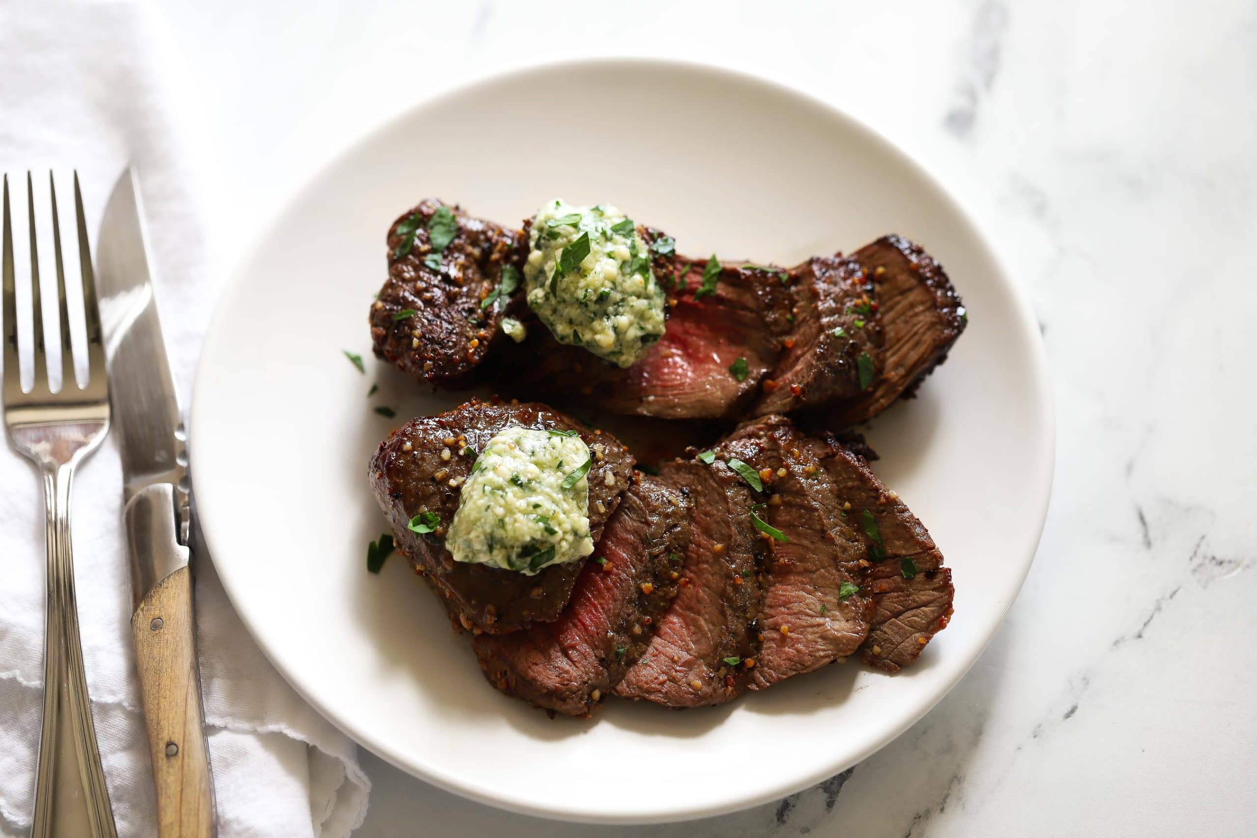 air fryer steak on white plate with butter