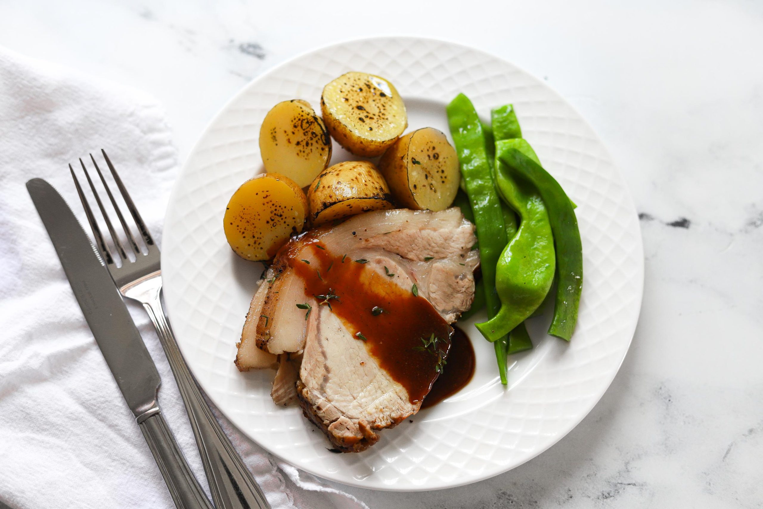 pork loin plated with green beans, potatoes, and glaze