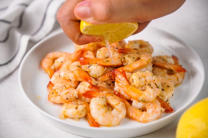 squeezing lemon half over cooked shrimp