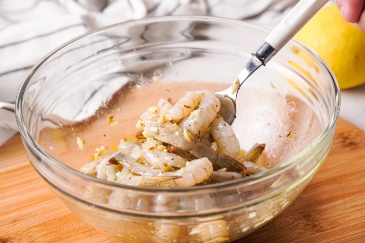 tossing shrimp in garlic butter with spoon