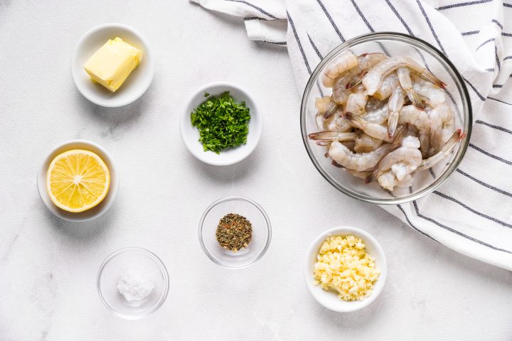 Ingredients for air fryer shrimp in individual bowls on white background